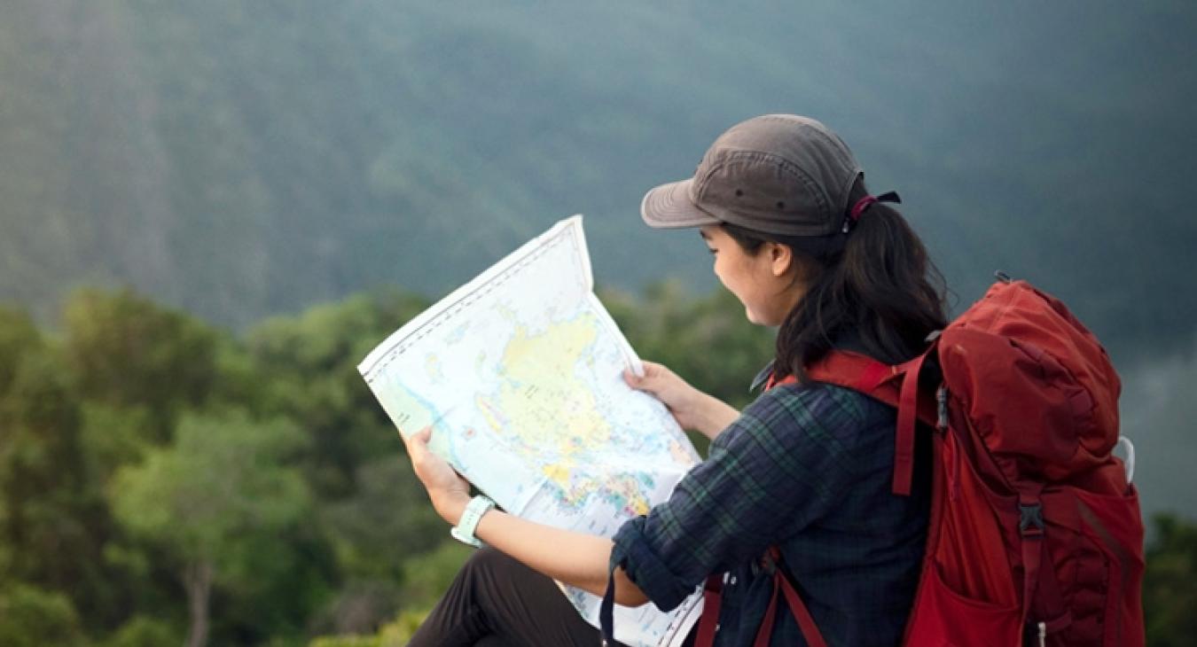 woman sitting on a mountain while looking at a map