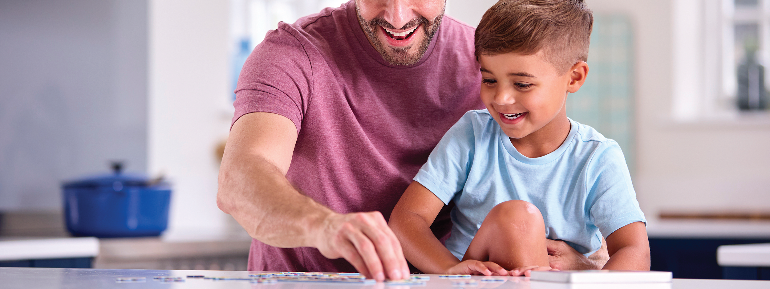 father and son working on a puzzle at the kitchen table