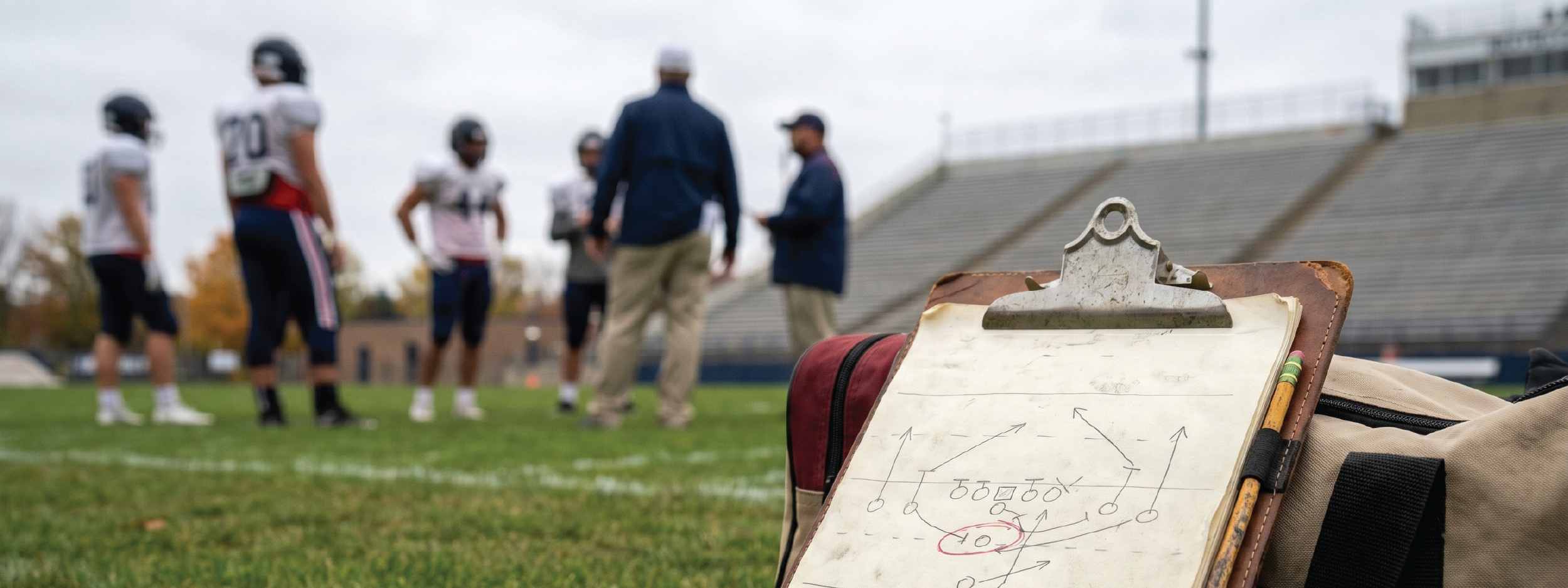 playbook resting against a duffle with football players in background